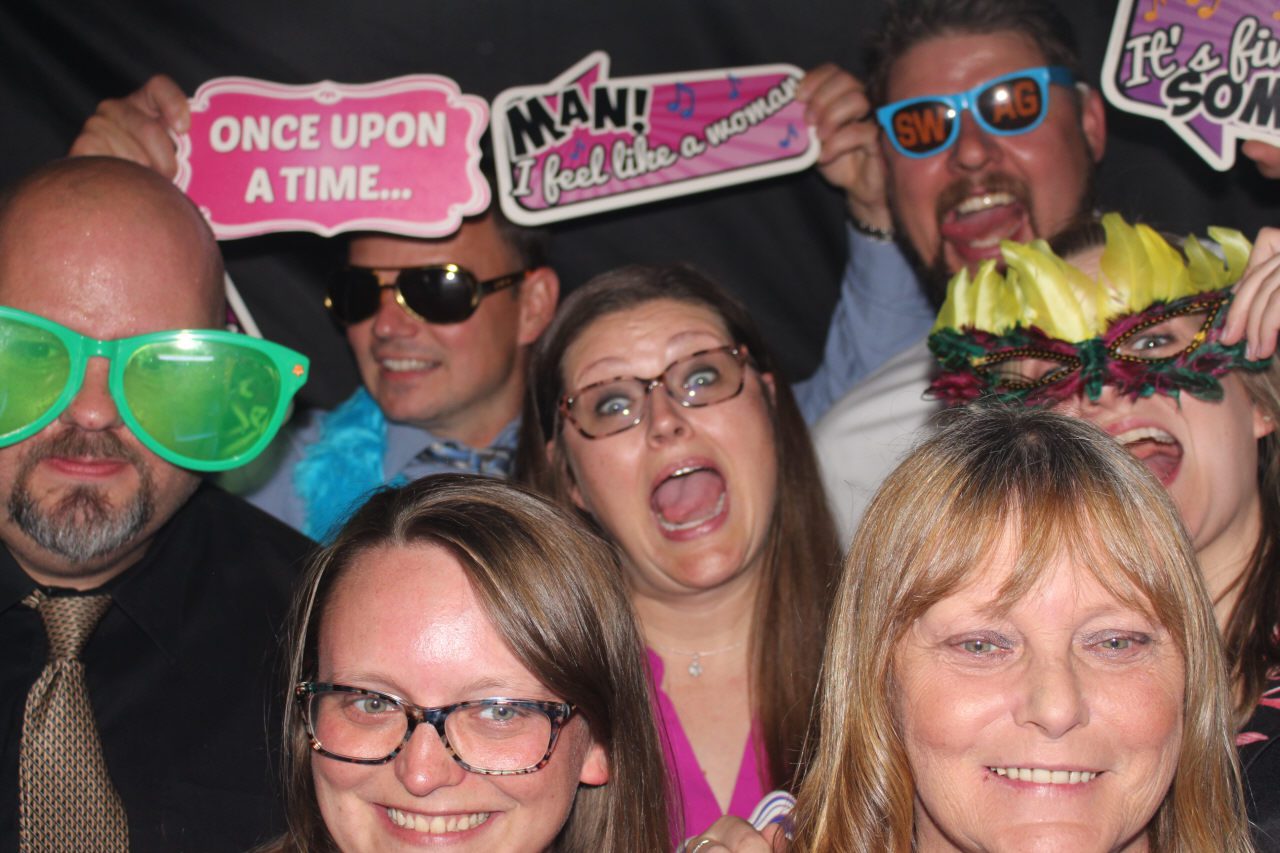 A group of friends having fun with photo booth props and glasses.